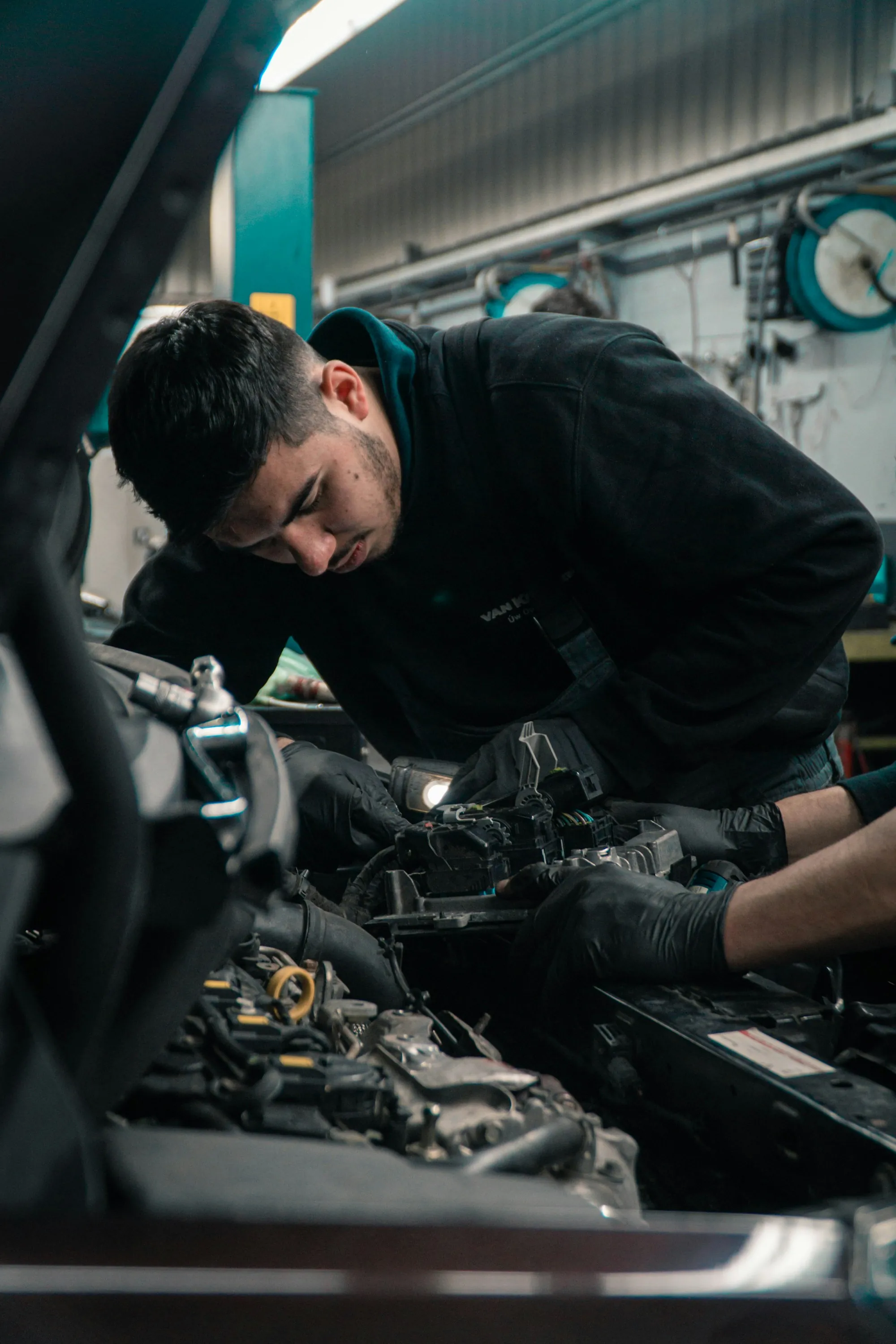 Mechanic leaning over an open engine bay inspecting components