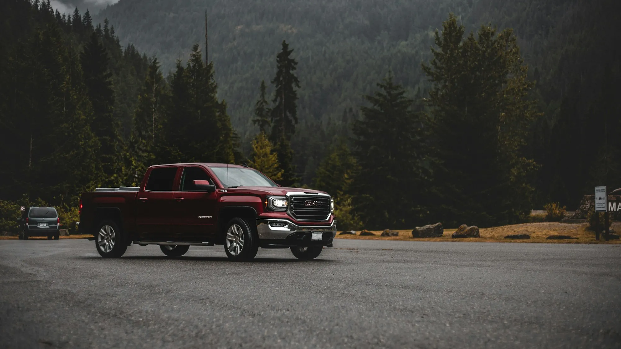 Red pickup truck on a mountain lot surrounded by pine trees