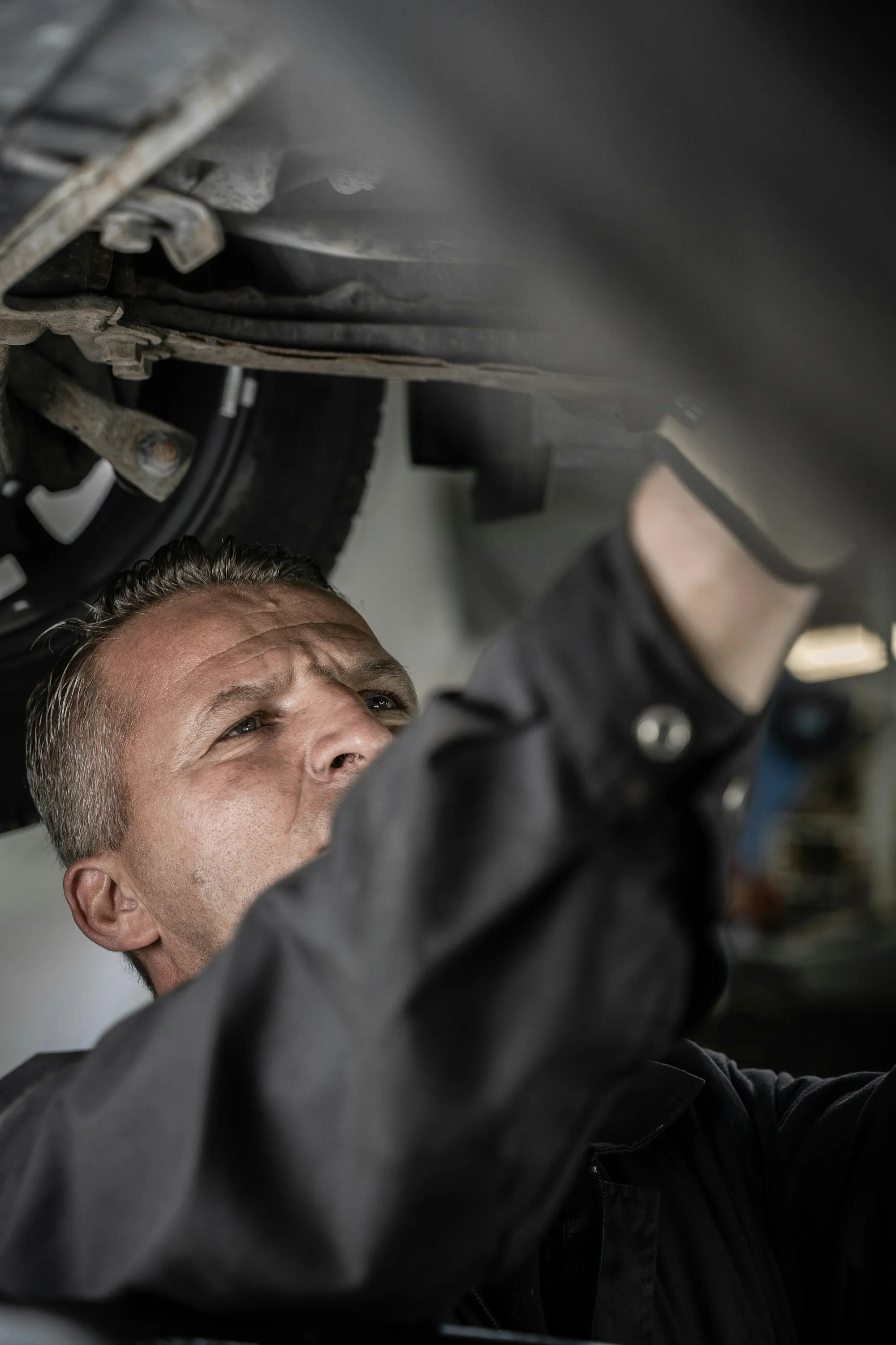 Mechanic working beneath a raised vehicle in a bright shop