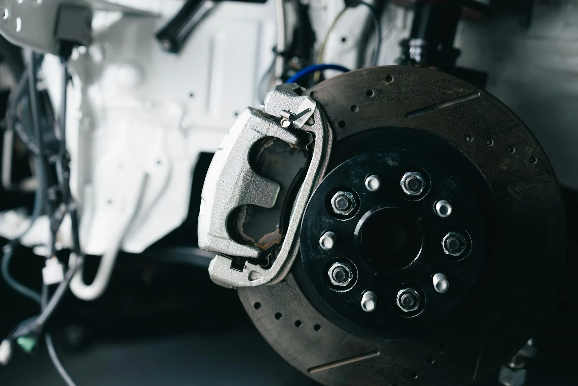 Brake caliper and drilled rotor on a raised vehicle